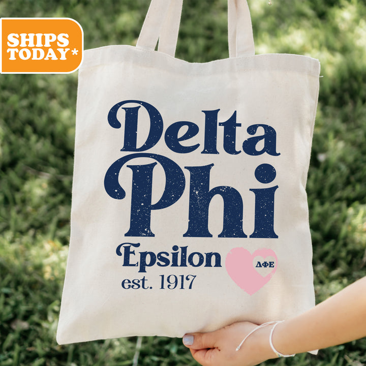 a person holding a tote bag with delta phi on it