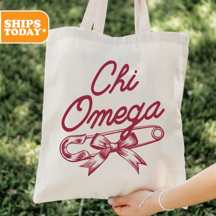 a person holding a tote bag that says chi omega
