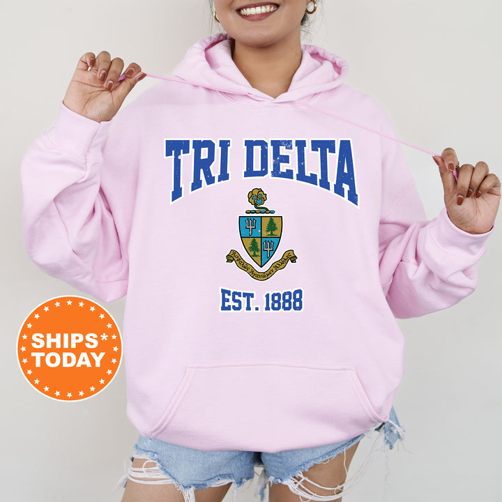 a woman wearing a pink hoodie with the words tri delta on it