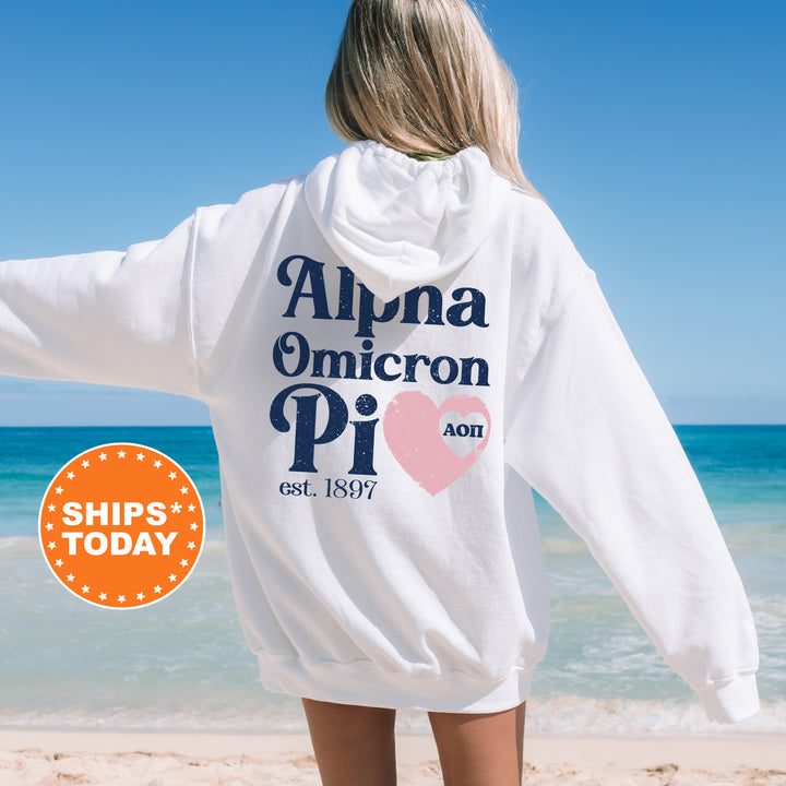 a woman standing on a beach wearing a white sweatshirt