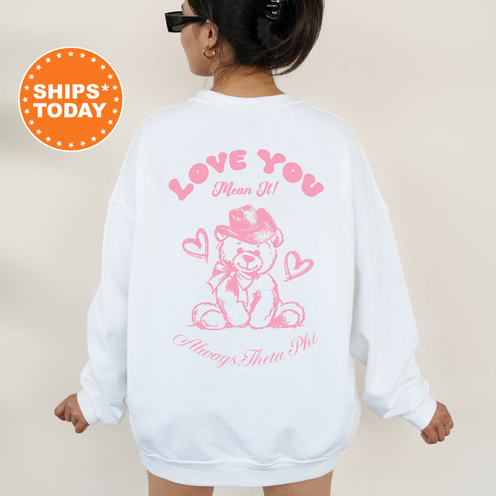 a woman wearing a white sweatshirt with a pink teddy bear on it