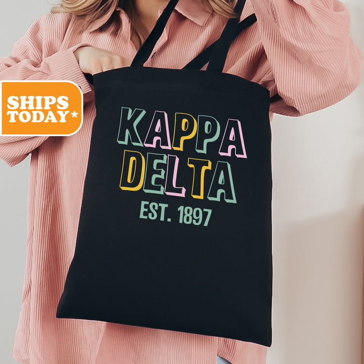 a woman holding a black kapa delta tote bag