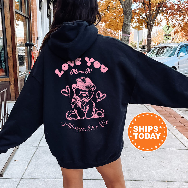 a woman wearing a black hoodie with a pink teddy bear on it