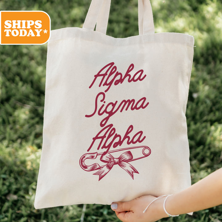 a person holding a tote bag with the words, alphabet, and scissors