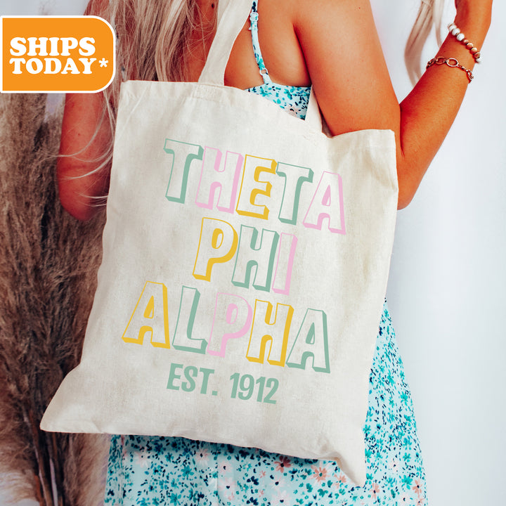 a woman holding a white bag with the words delta phi aloha on it