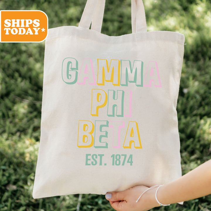 a person holding a tote bag with the words gumma phi beja est