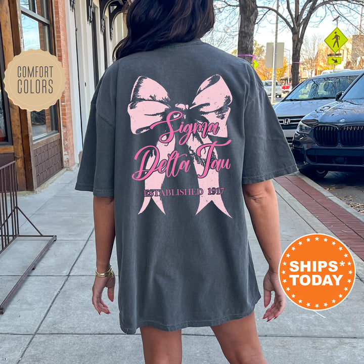 a woman is walking down the sidewalk wearing a t - shirt with a pink bow