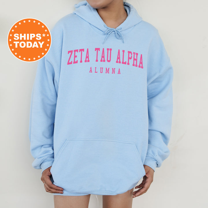 a woman wearing a blue sweatshirt with the words zeta tau alpha on it