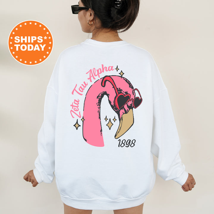 a woman wearing a white sweatshirt with a pink flamingo on it