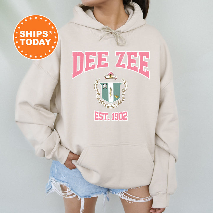 a woman wearing a beige hoodie with a crest on it