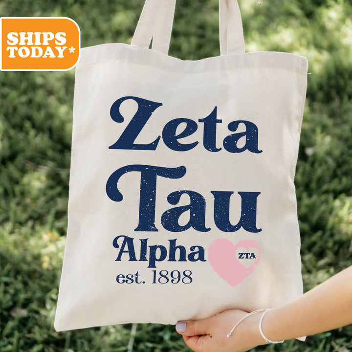 a person holding a tote bag that says zeta tau alpha