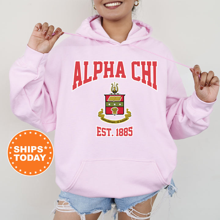 a woman wearing a pink hoodie with a crest on it