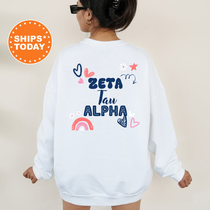 a woman wearing a white sweatshirt with the words zeta tau alpha on it