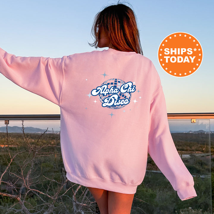 A woman wearing a pink sweatshirt with the text "Alpha Chi Dio" printed on it, standing on a balcony overlooking a scenic landscape.