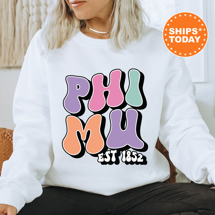 a woman sitting on a couch wearing a white sweatshirt with the phrase phi phi phi