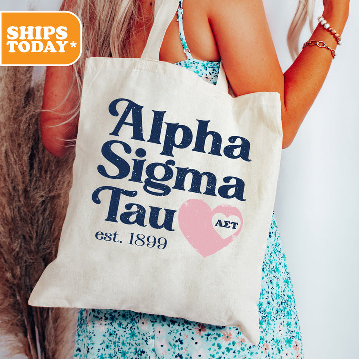 a woman holding a tote bag with the words alpha sigma tau