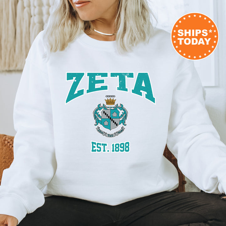 a woman sitting on a chair wearing a zeta sweatshirt