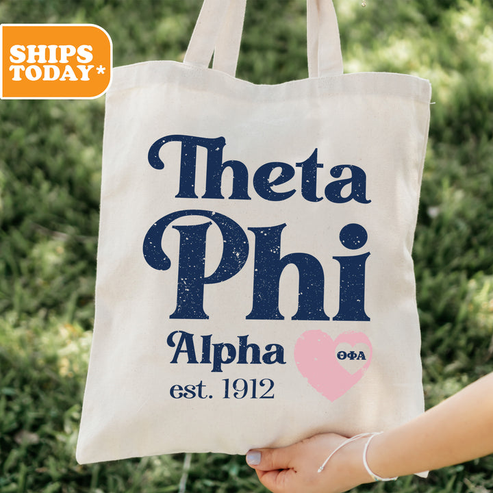 a person holding a tote bag with the words, thea phi, and