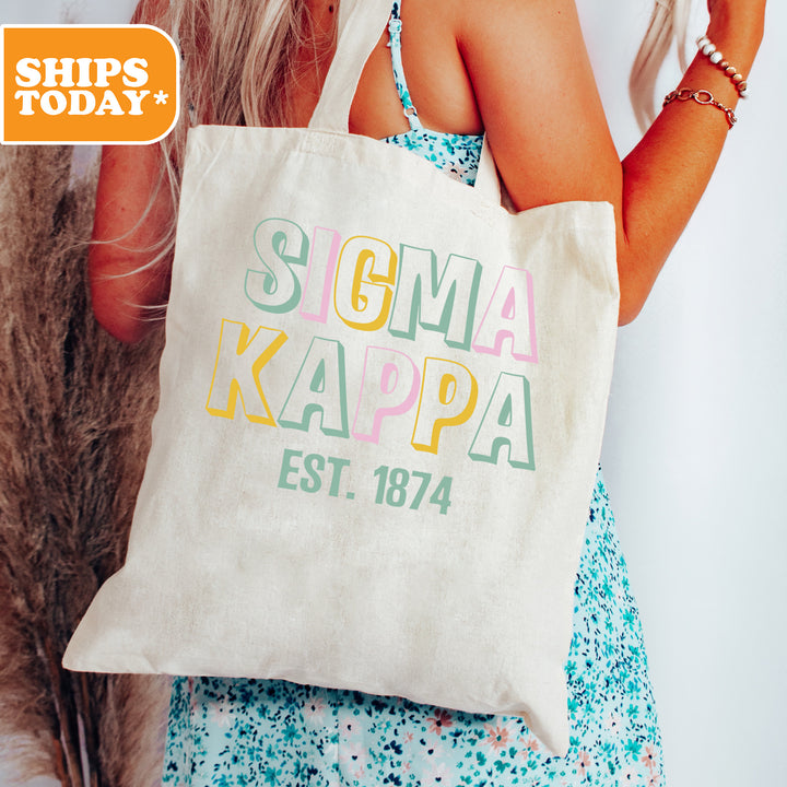 a woman holding a tote bag with the words soma kappa est