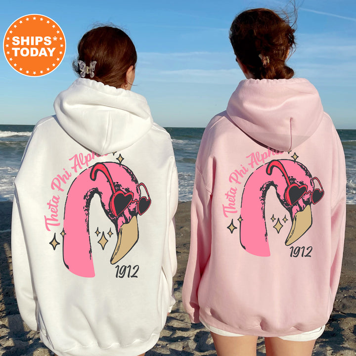two women wearing pink and white sweatshirts on the beach