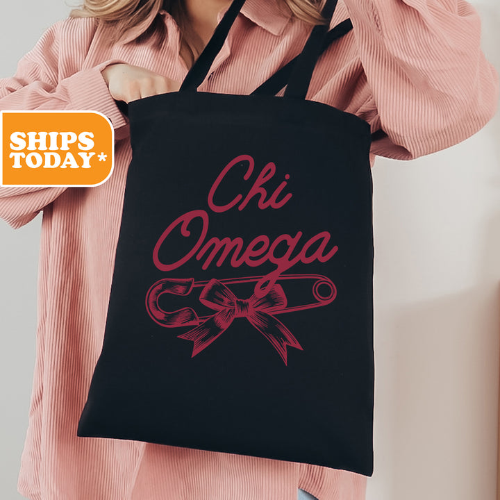 a woman holding a black tote bag with the words chi omega on it