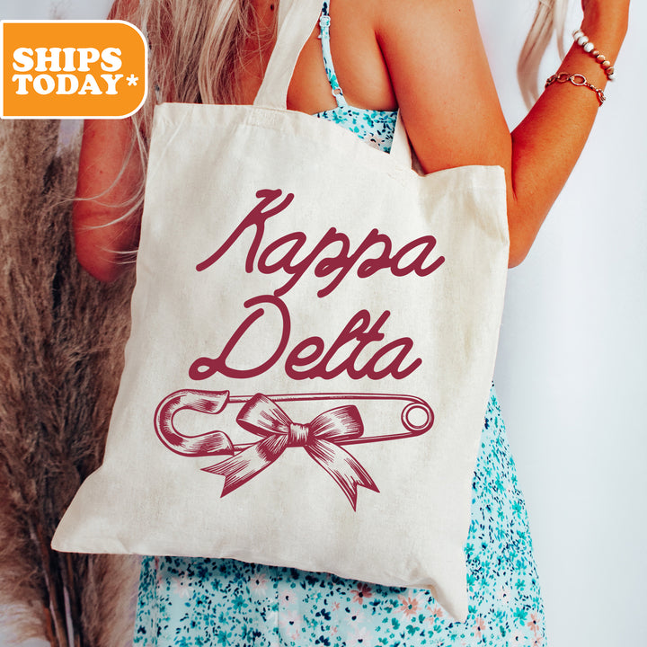 a woman holding a tote bag with a ribbon on it