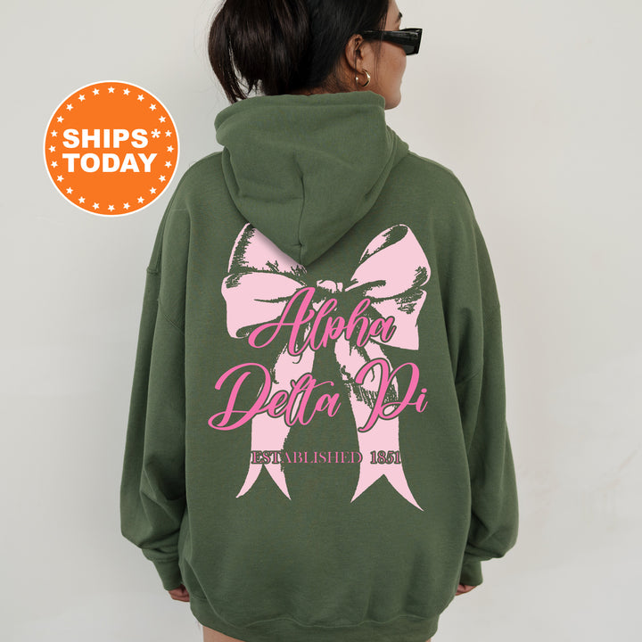 a woman wearing a green sweatshirt with a pink bow on it