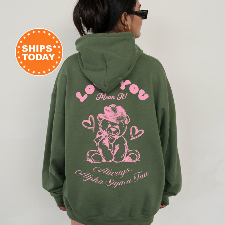 a woman wearing a green hoodie with a pink teddy bear on it