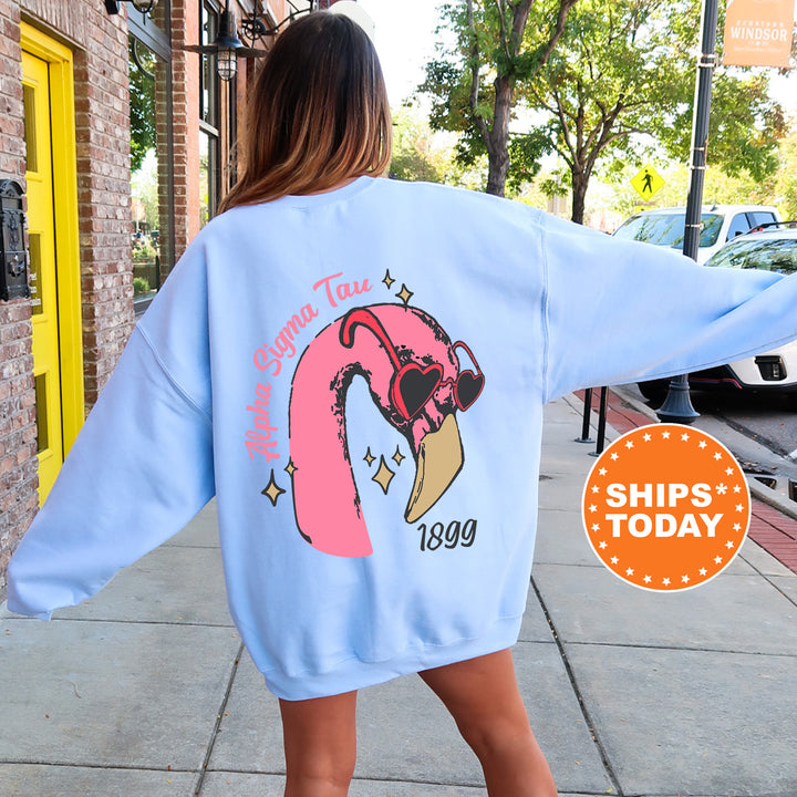 a woman walking down a sidewalk wearing a pink flamingo sweatshirt