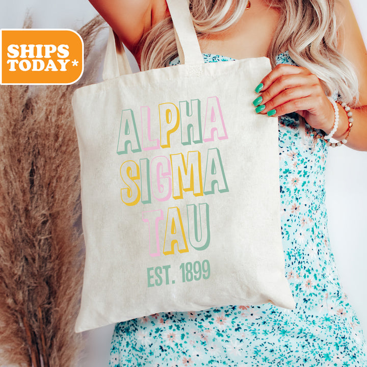 a woman holding a tote bag with the words, alpha, sisma tau