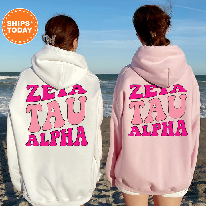 two women wearing pink and white hoodies on the beach