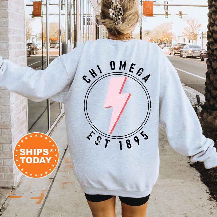 a woman walking down a sidewalk wearing a sweatshirt with a lightning bolt on it