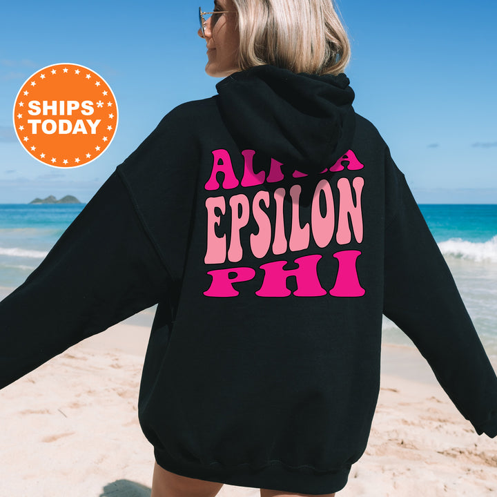 a woman in a black hoodie is walking on the beach