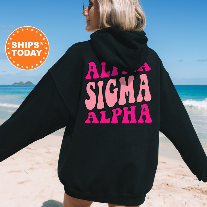a woman in a black hoodie is walking on the beach