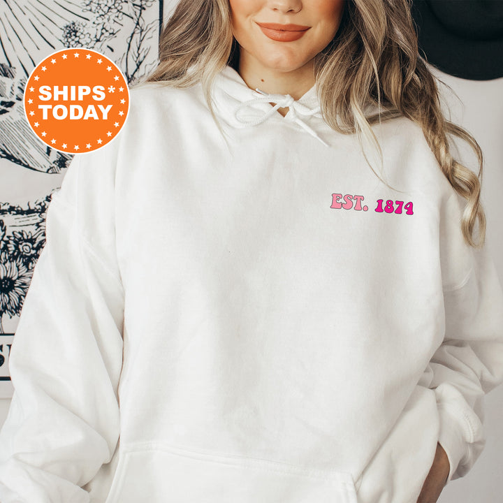 a woman wearing a white hoodie with a pink patch on the chest
