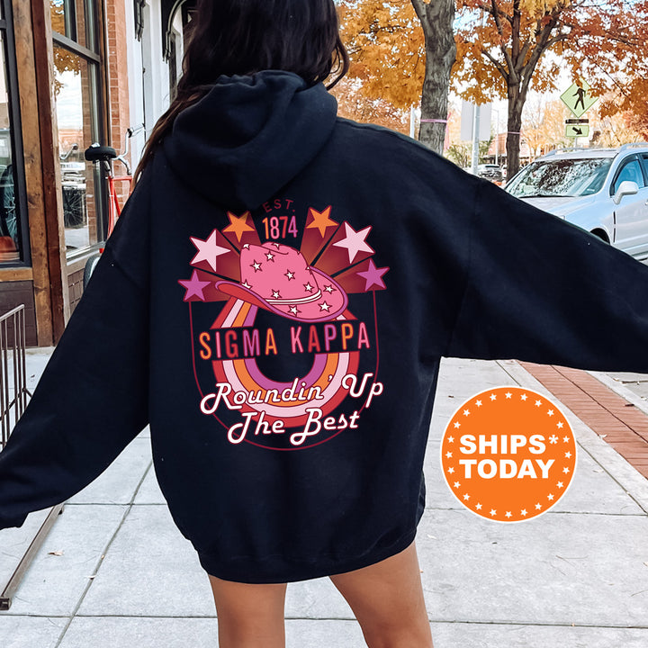a woman walking down a sidewalk wearing a black hoodie