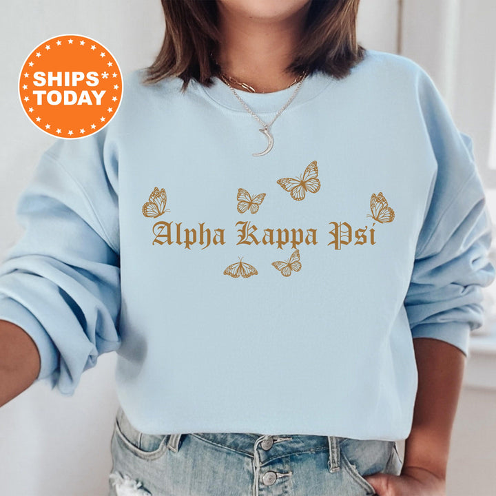 a woman wearing a light blue sweatshirt with gold butterflies on it