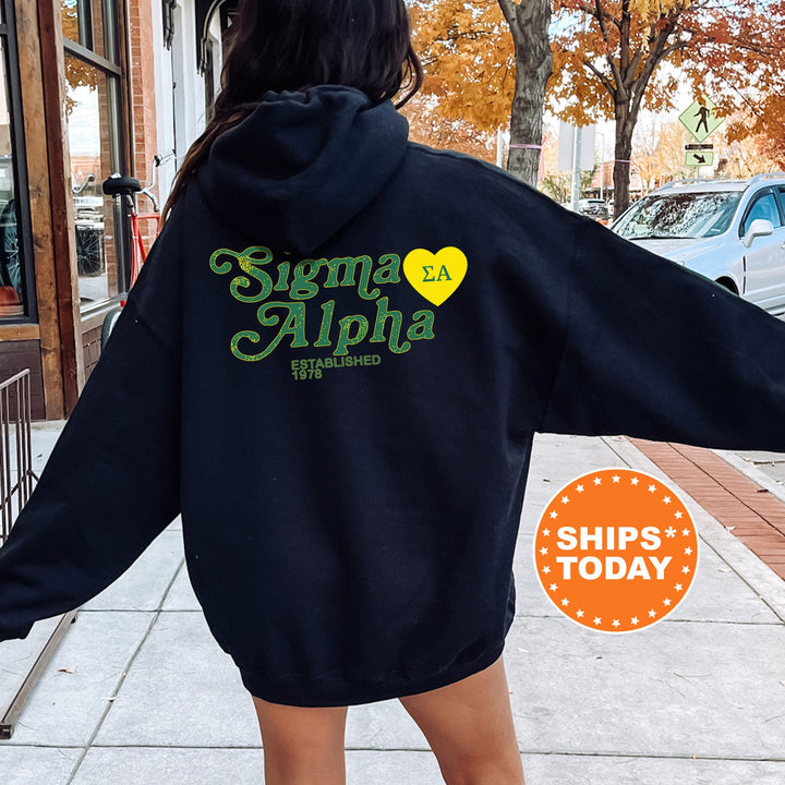 a woman walking down a sidewalk wearing a black hoodie