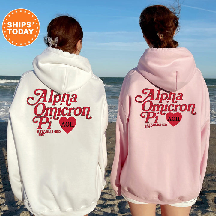 two women wearing pink and white hoodies on the beach