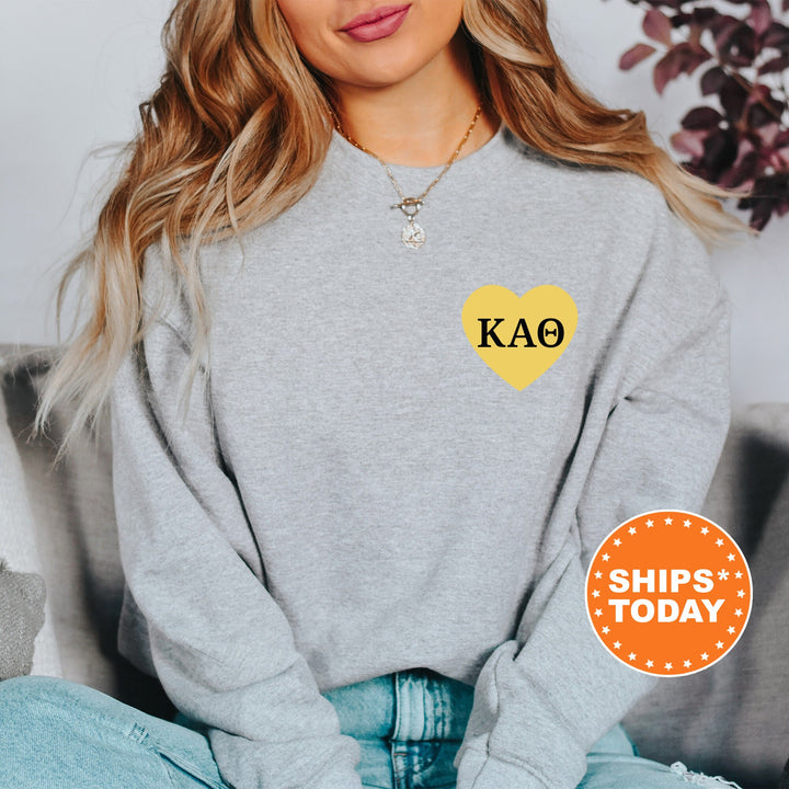 a woman sitting on a couch wearing a grey sweater with a yellow heart on it
