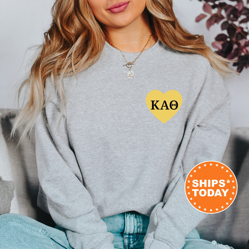 a woman sitting on a couch wearing a grey sweater with a yellow heart on it