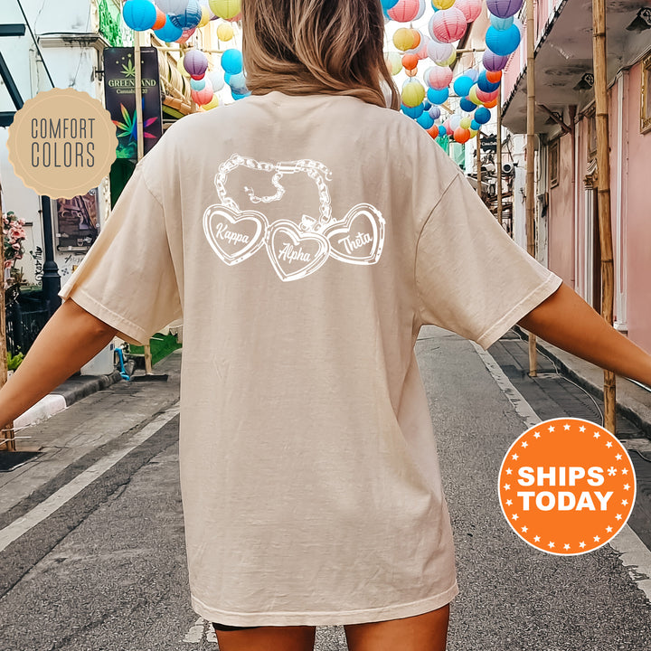 A person wearing a beige t-shirt with a graphic design on the back, standing on a street with colorful lanterns hanging overhead.