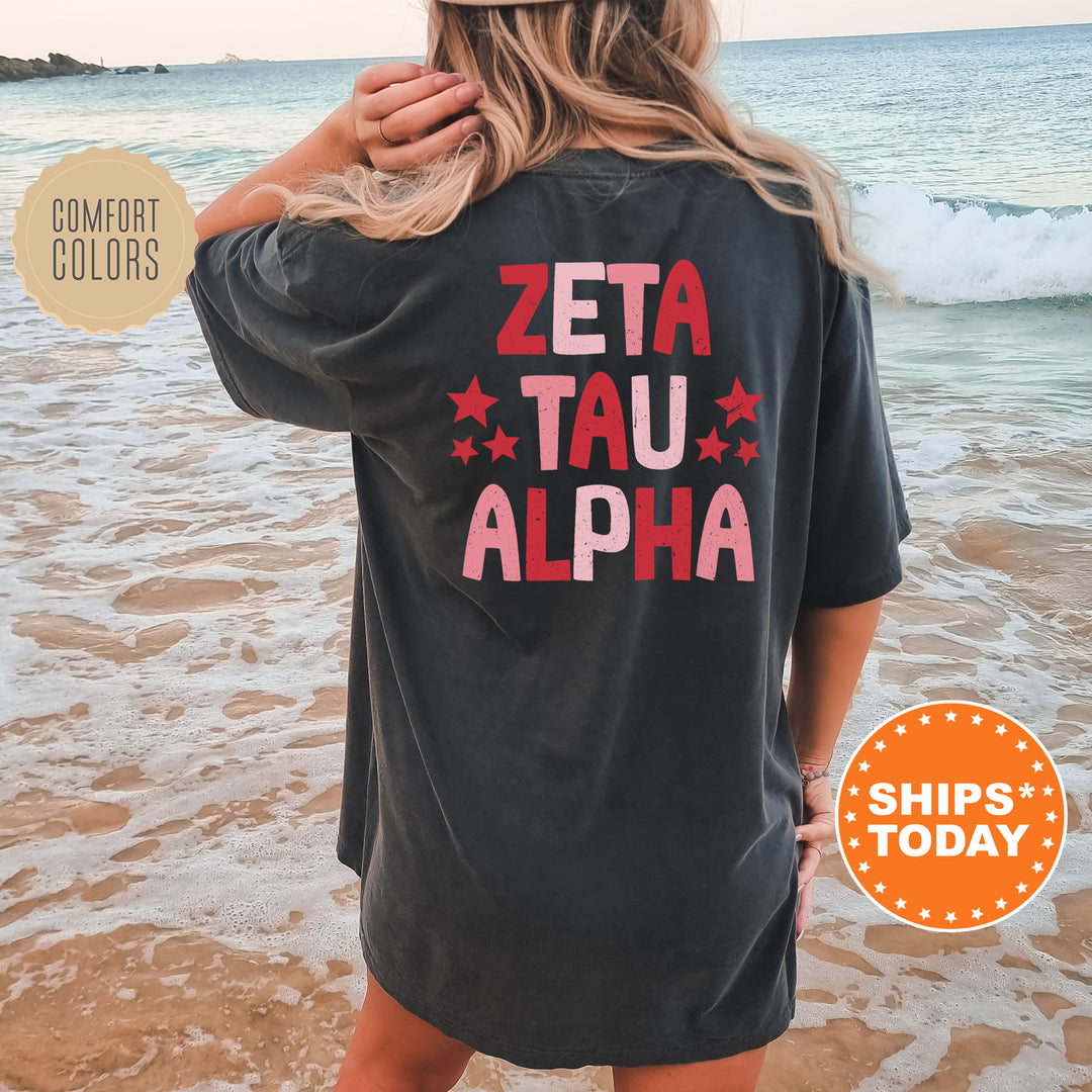 a woman standing on the beach wearing a zeta tau alpha shirt