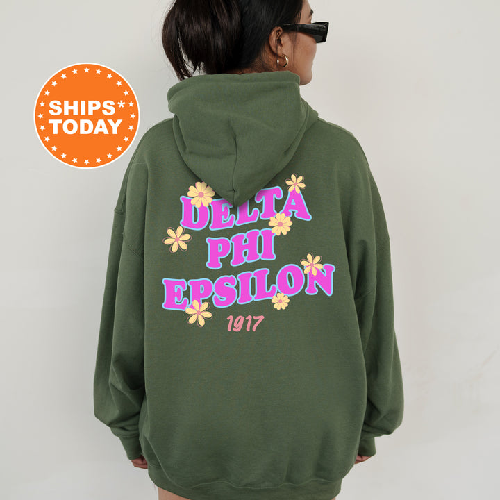 A person wearing a green hoodie with text and flowers printed on it.