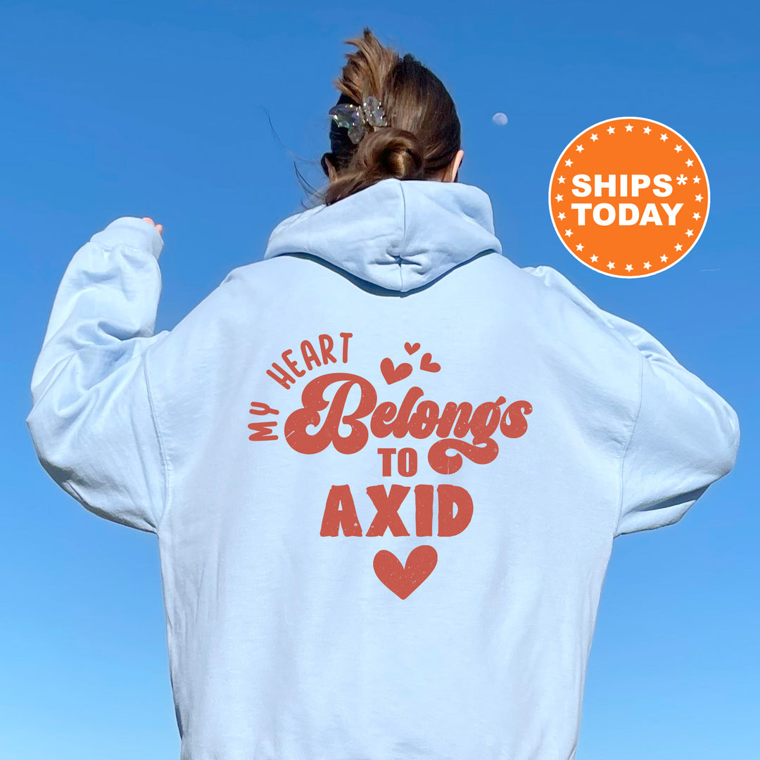 a woman wearing a white hoodie that says i heart belongs to axid