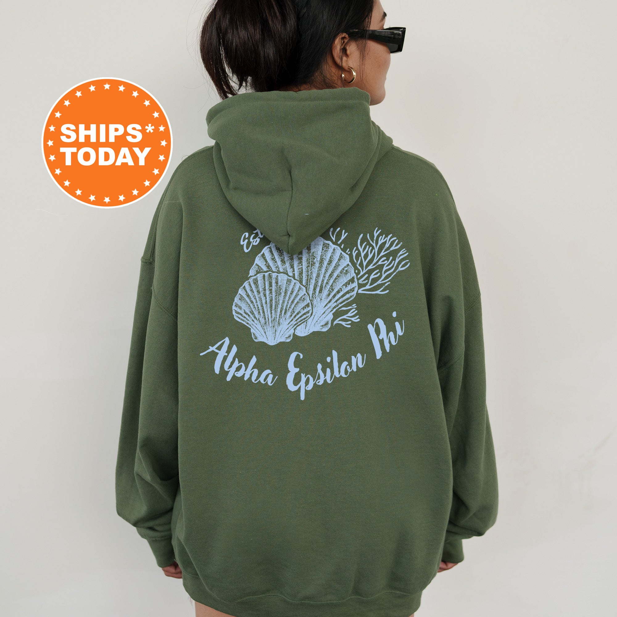 A person wearing a green hoodie with a graphic design of seashells and the text 