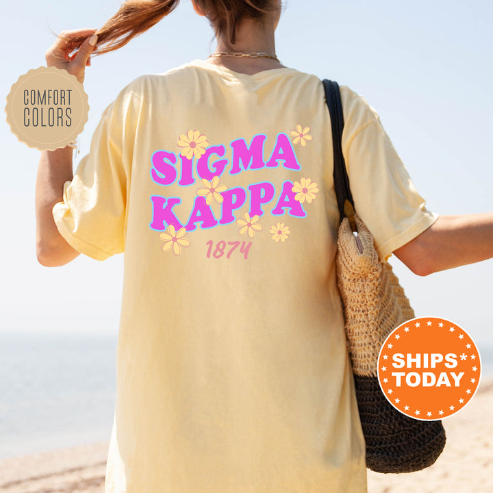 A person wearing a yellow t-shirt with the text "SIGMA KAPPA 1874" printed on it, standing on a beach.
