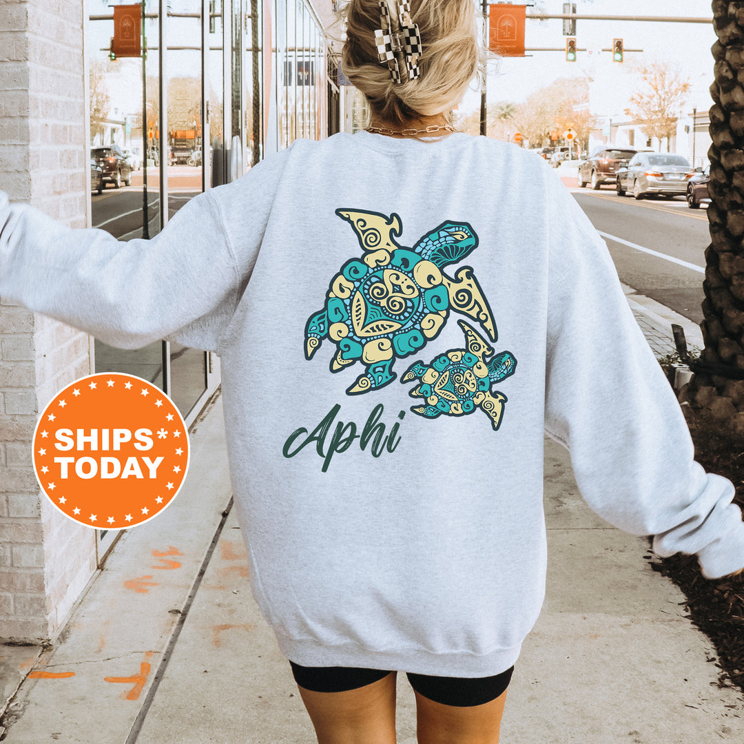 A person wearing a grey sweatshirt with a colorful turtle design on the back, standing on a sidewalk with a traffic light in the background.