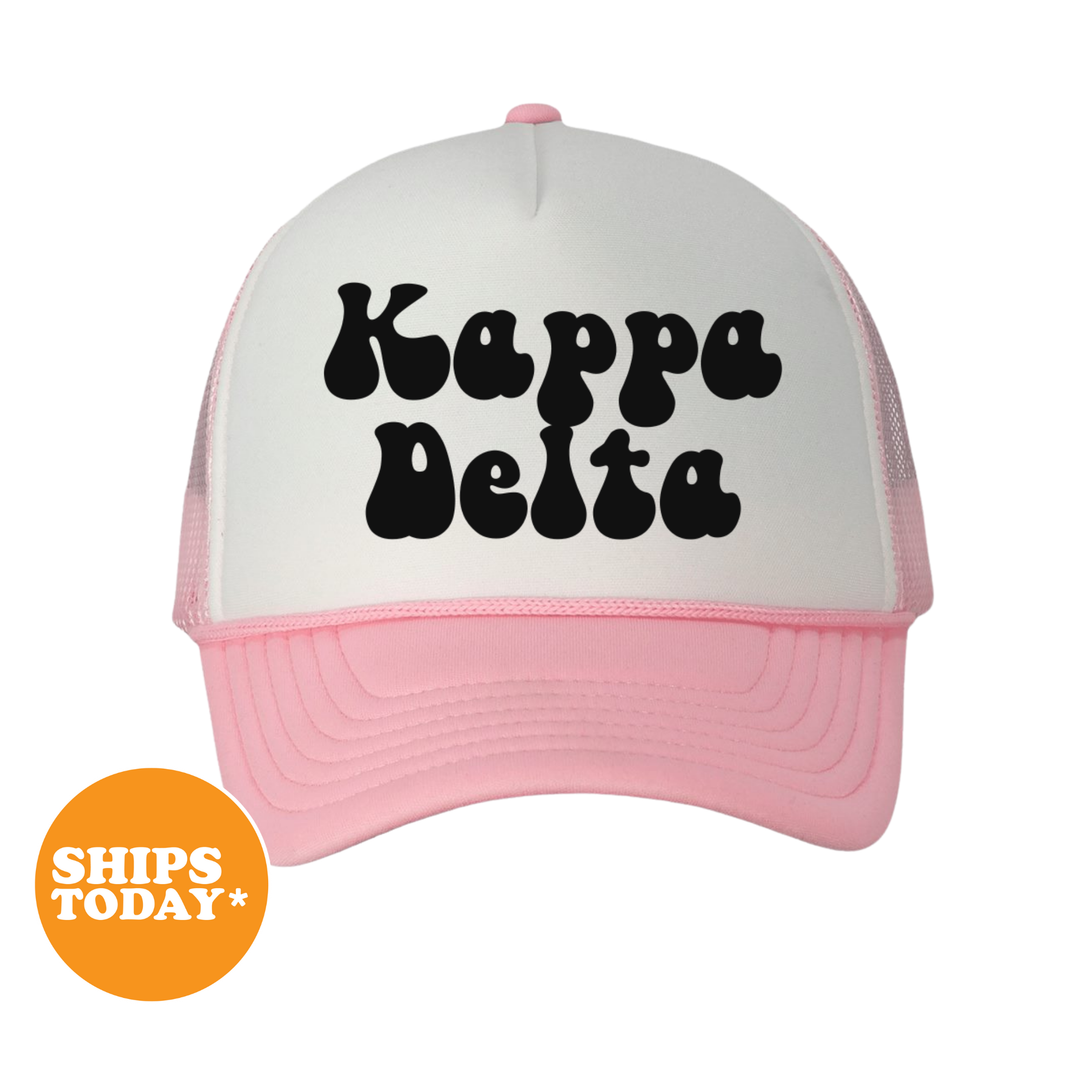 A pink and white baseball cap with the text " Kappa Delta" printed on it.