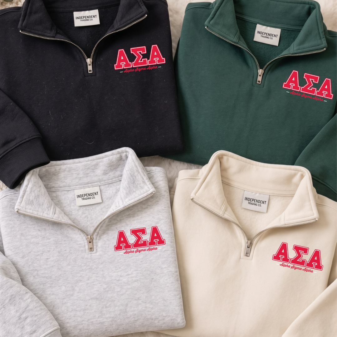 a collection of four zip-up sweatshirts, each with the Greek letters 'ΑΕΛΑ' printed on them. The sweatshirts are arranged in a row, with the first one being black, the second one being gray, the third one being green, and the fourth one being beige. Each sweatshirt has a label on the front, indicating that they are part of a collection or merchandise.